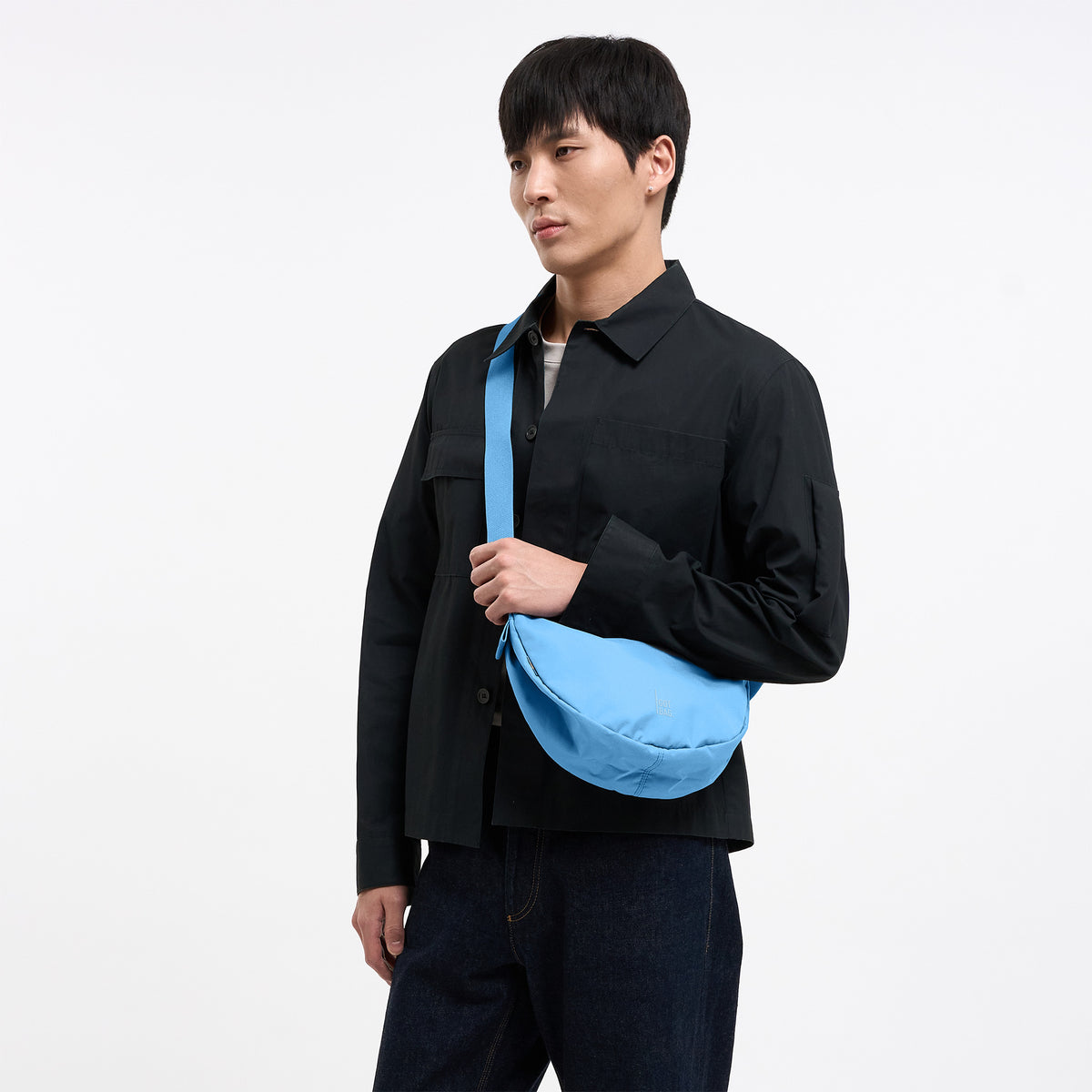 MOON BAG SMALL Tasche in aqua (leuchtendes Hellblau) von einem Mann crossbody getragen.