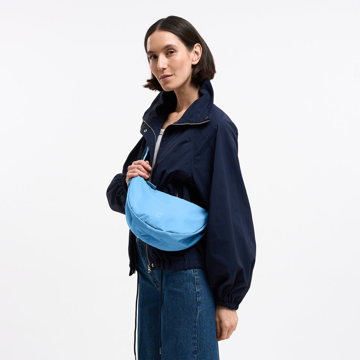 MOON BAG SMALL Tasche in aqua (leuchtendes Hellblau) von einer Frau crossbody getragen.