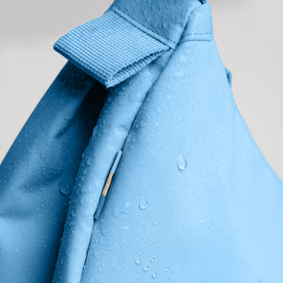 MOON BAG SMALL Tasche in aqua (leuchtendes Hellblau) Detailaufnahme mit Wassertropfen auf dem Stoff.