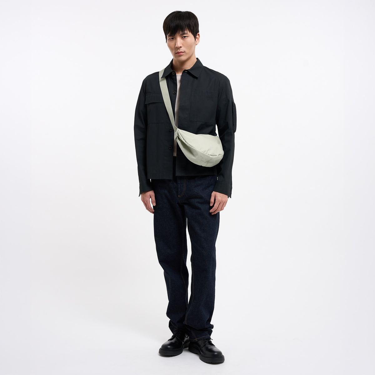 MOON BAG SMALL Tasche in beach foam (helles Grau) von einem Mann crossbody getragen.