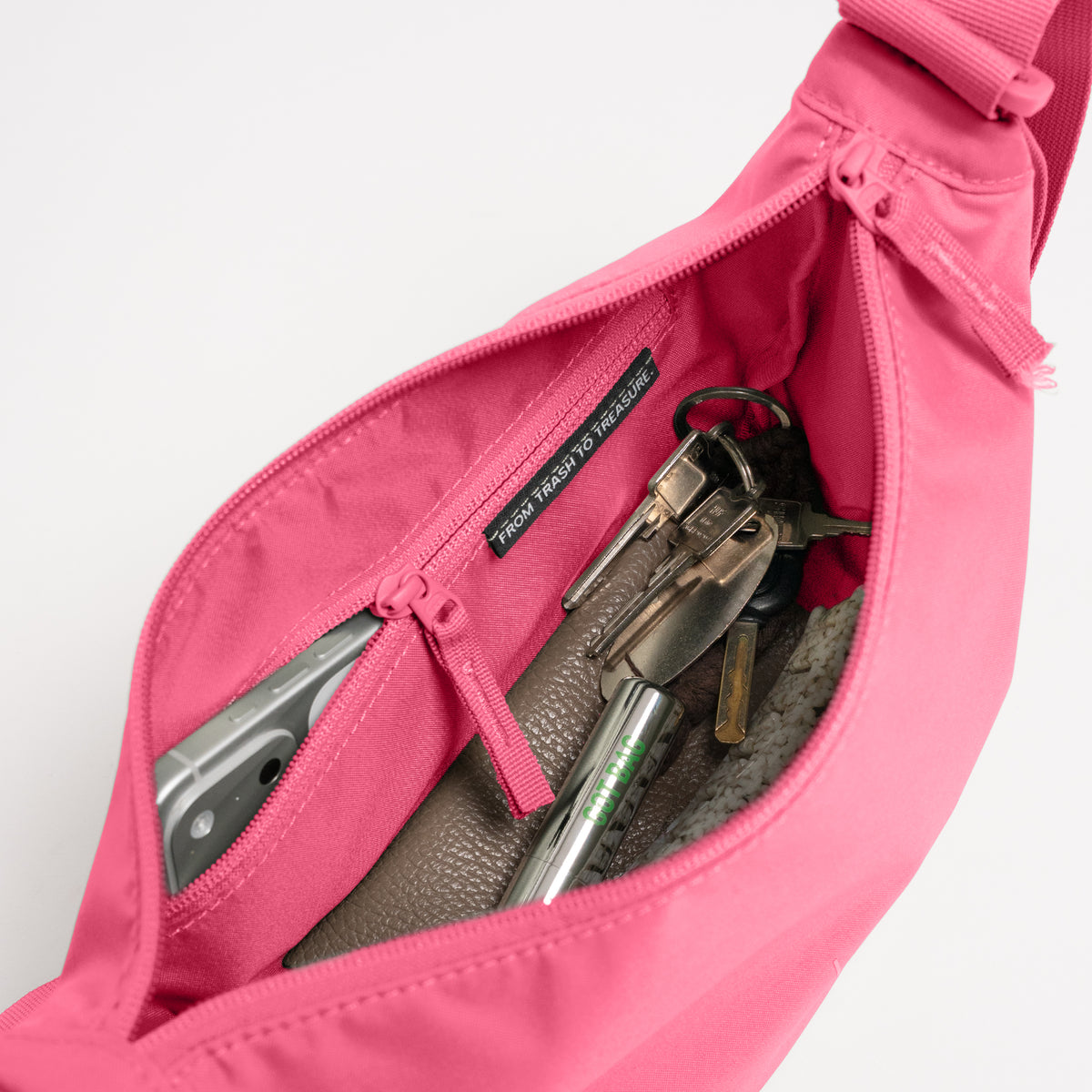 MOON BAG SMALL Tasche in salina pink (leuchtendes Pink) als Detailaufnahme des Innenraums mit Handy, Schlüsseln und Stift.
