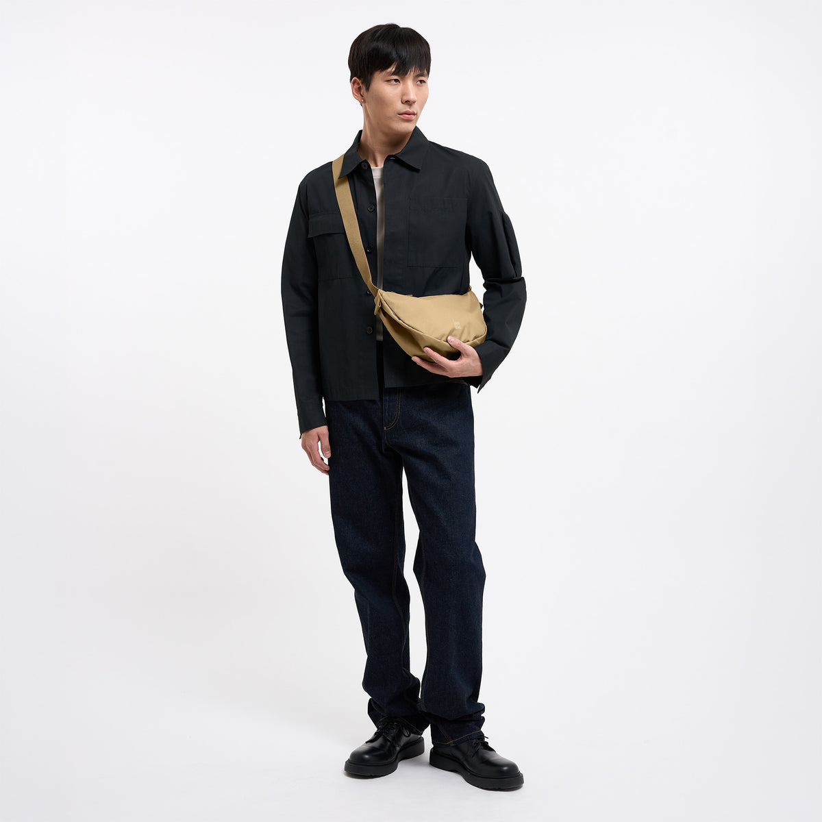 MOON BAG SMALL Tasche in sea moss (warmes Beige-Khaki) von einem Mann crossbody getragen.