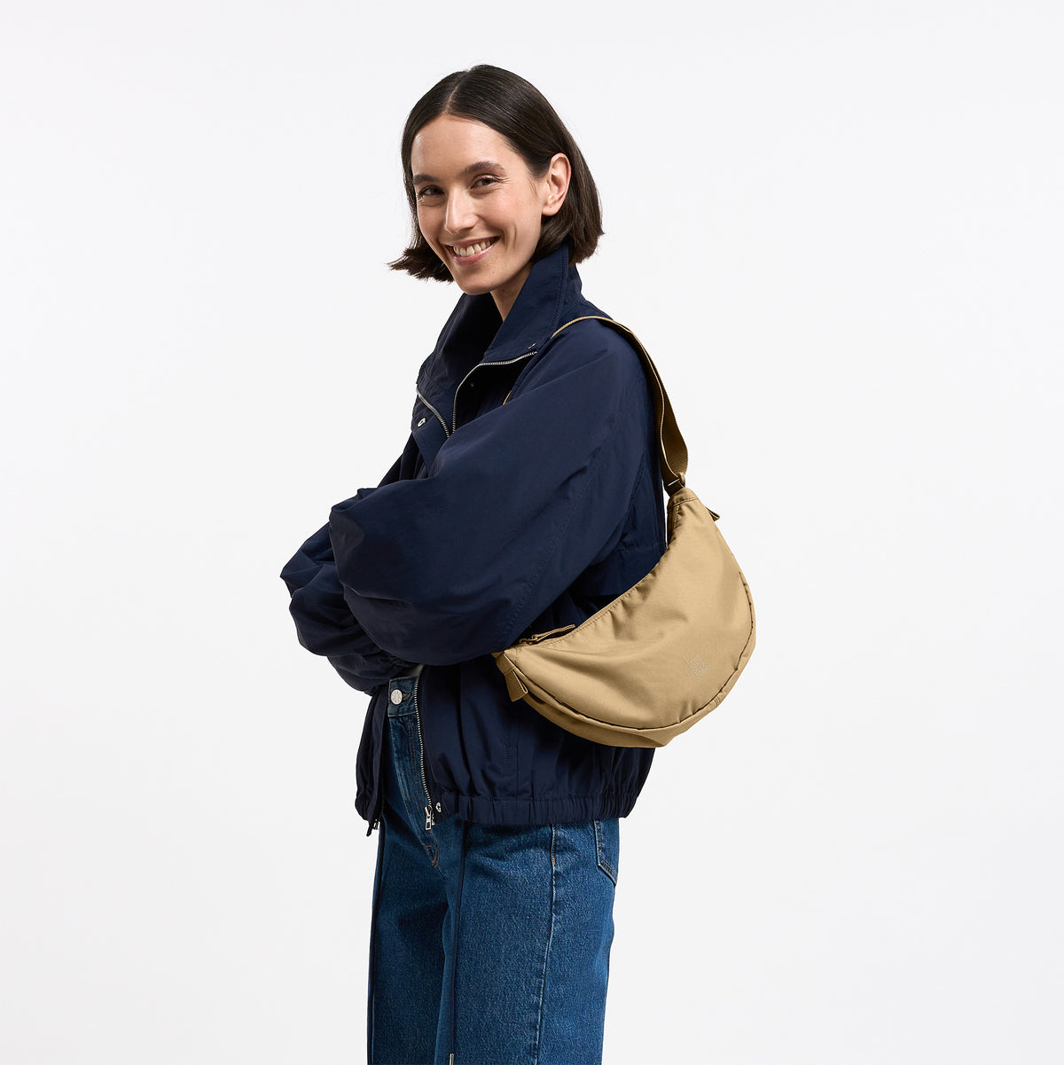 MOON BAG SMALL Tasche in sea moss (warmes Beige-Khaki) von einer Frau crossbody getragen.