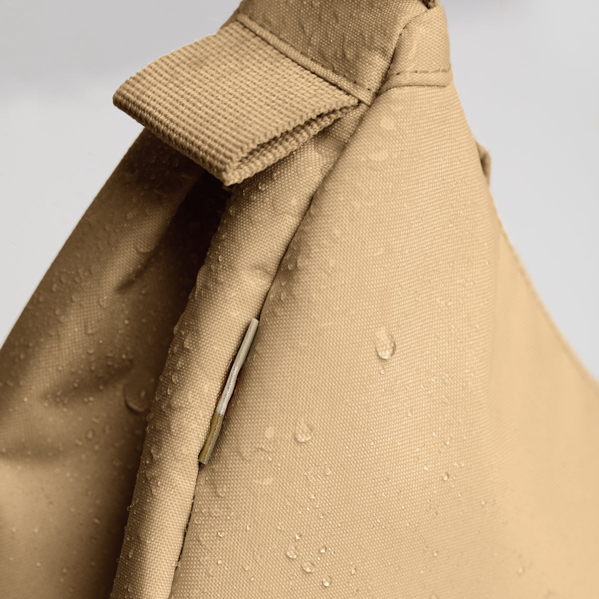 MOON BAG SMALL Tasche in sea moss (warmes Beige-Khaki), Detailaufnahme des wasserabweisenden Materials mit Wassertropfen.