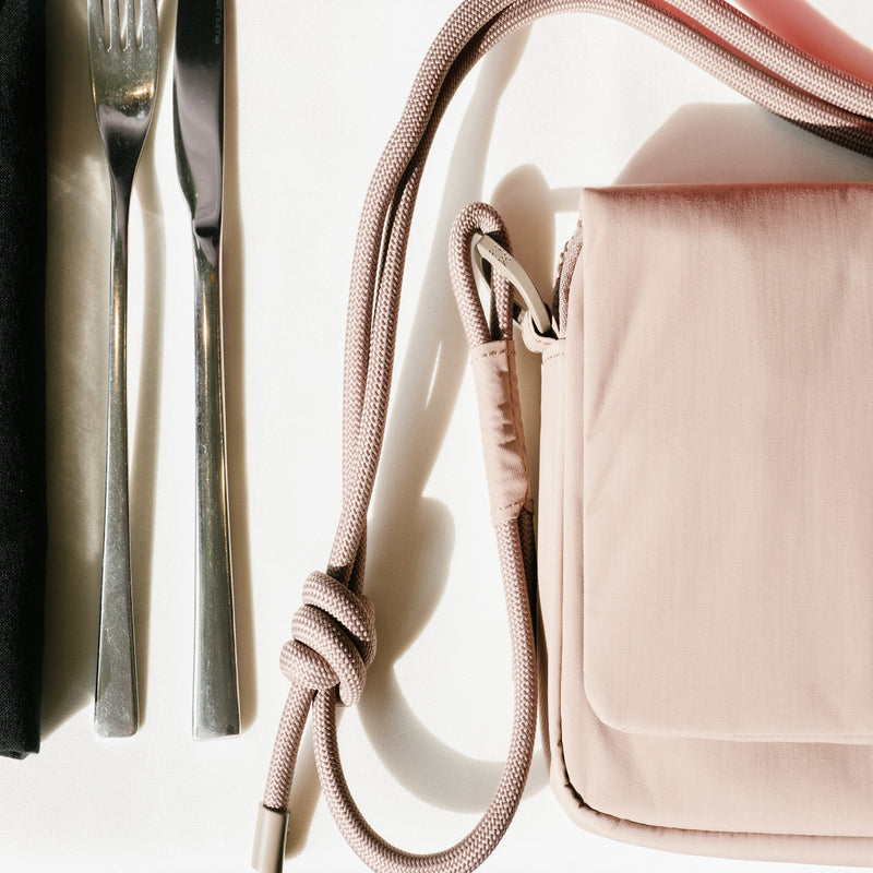 ESSENTIAL BAG EVENT bag next to cutlery on a white surface.