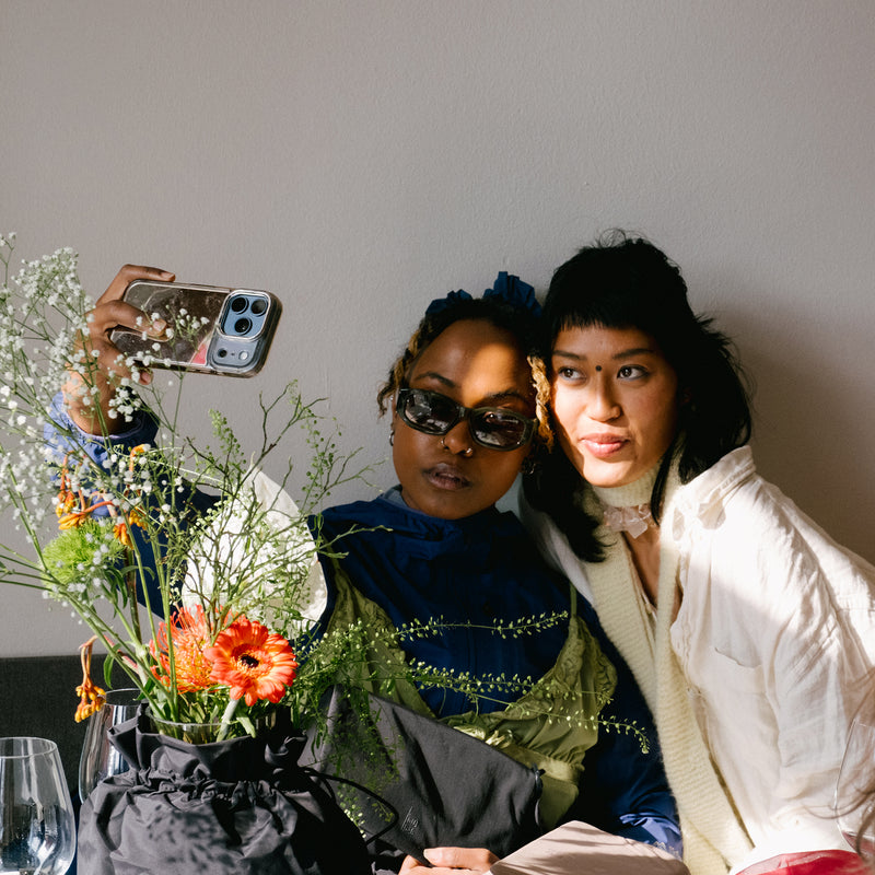 ESSENTIAL BAG bag used as a flower holder on a table by two women.