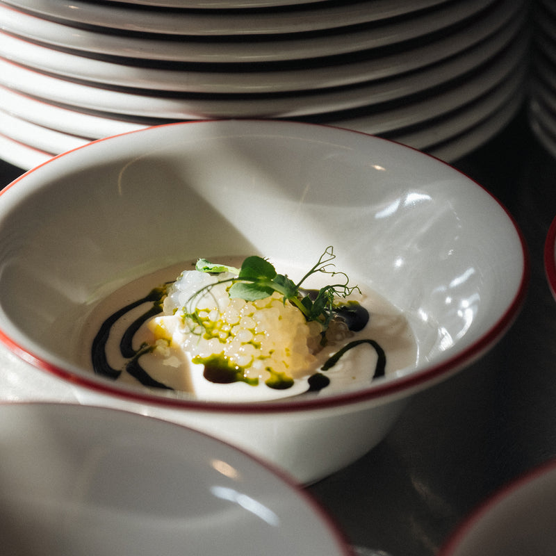 ESSENTIAL Accessories: A white bowl with creamy dish, green sauce, microgreens, and dark sauce swirls.