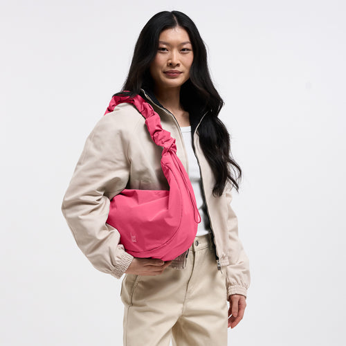MOON BAG RUFFLE Tasche in salina pink (leuchtendes Pink) von einer Frau crossbody getragen.