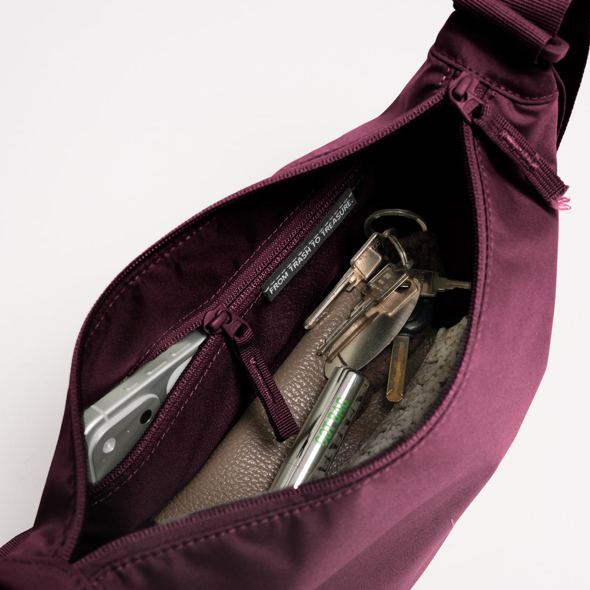 MOON BAG SMALL Tasche in kraken (Weinrot) Innenansicht mit Handy, Schlüsseln und dem Schriftzug FROM TRASH TO TREASURE.