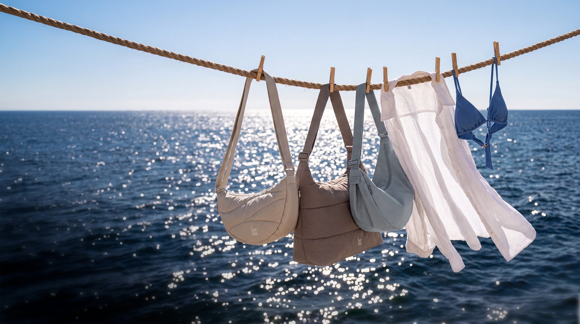 Three bags, a shirt, and a bikini top hang on a clothesline above the sea.
