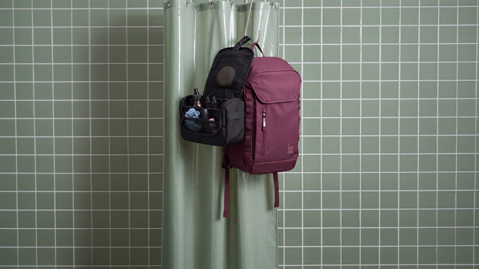 FREE SHOWER KIT accessories with open compartments and care products, hanging next to a backpack on a shower curtain rod.