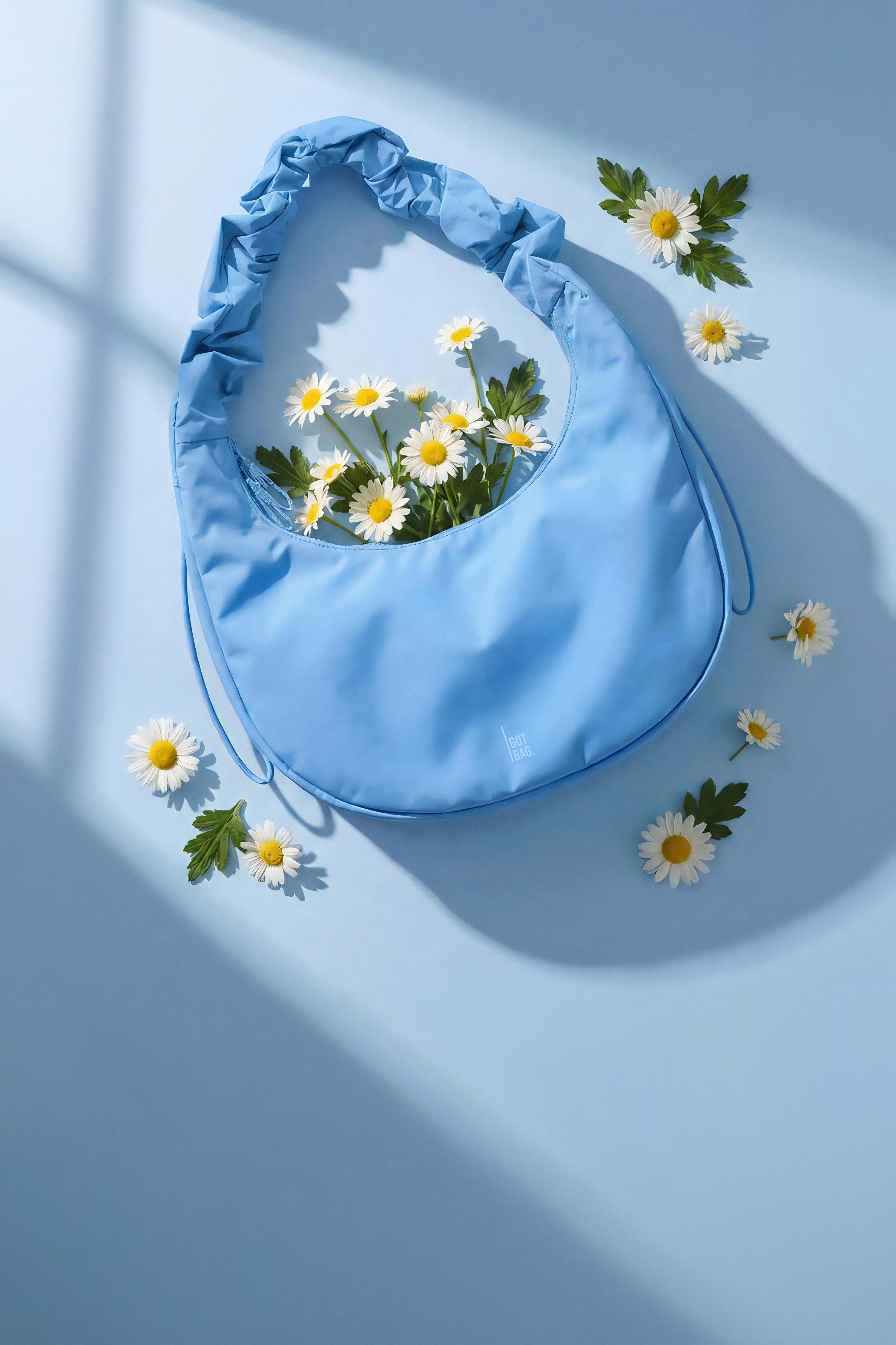 Tas met geplooide handgreep, gevuld met verse madeliefjes, op een bijpassende achtergrond met raamschaduwen.