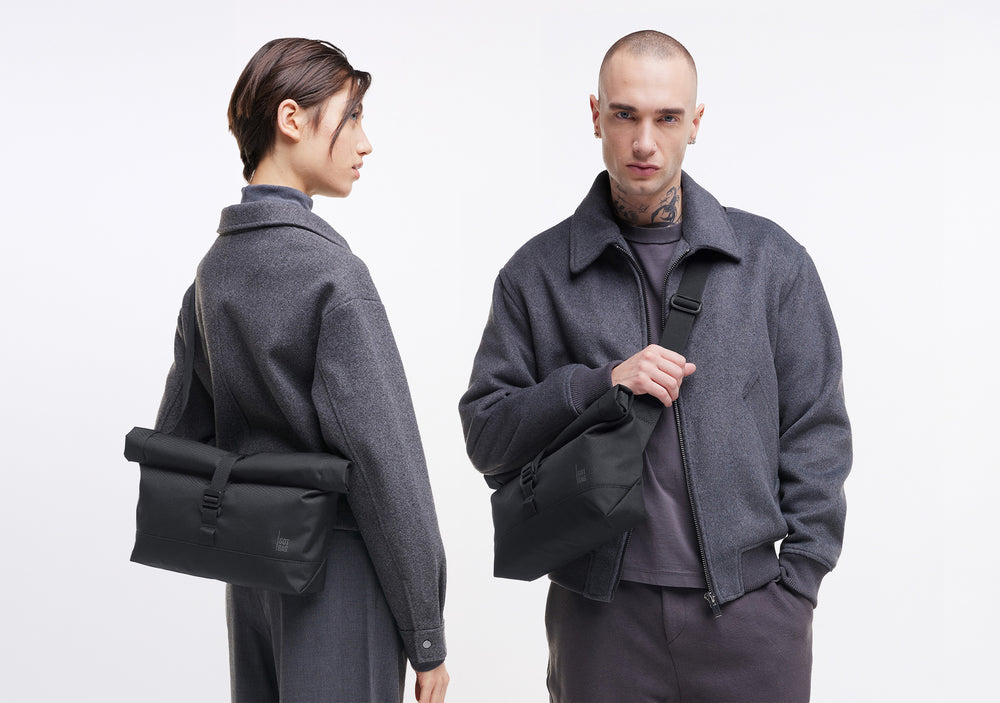 Dvě osoby, žena a muž, představují tašku, nošenou crossbody a drženou v ruce.