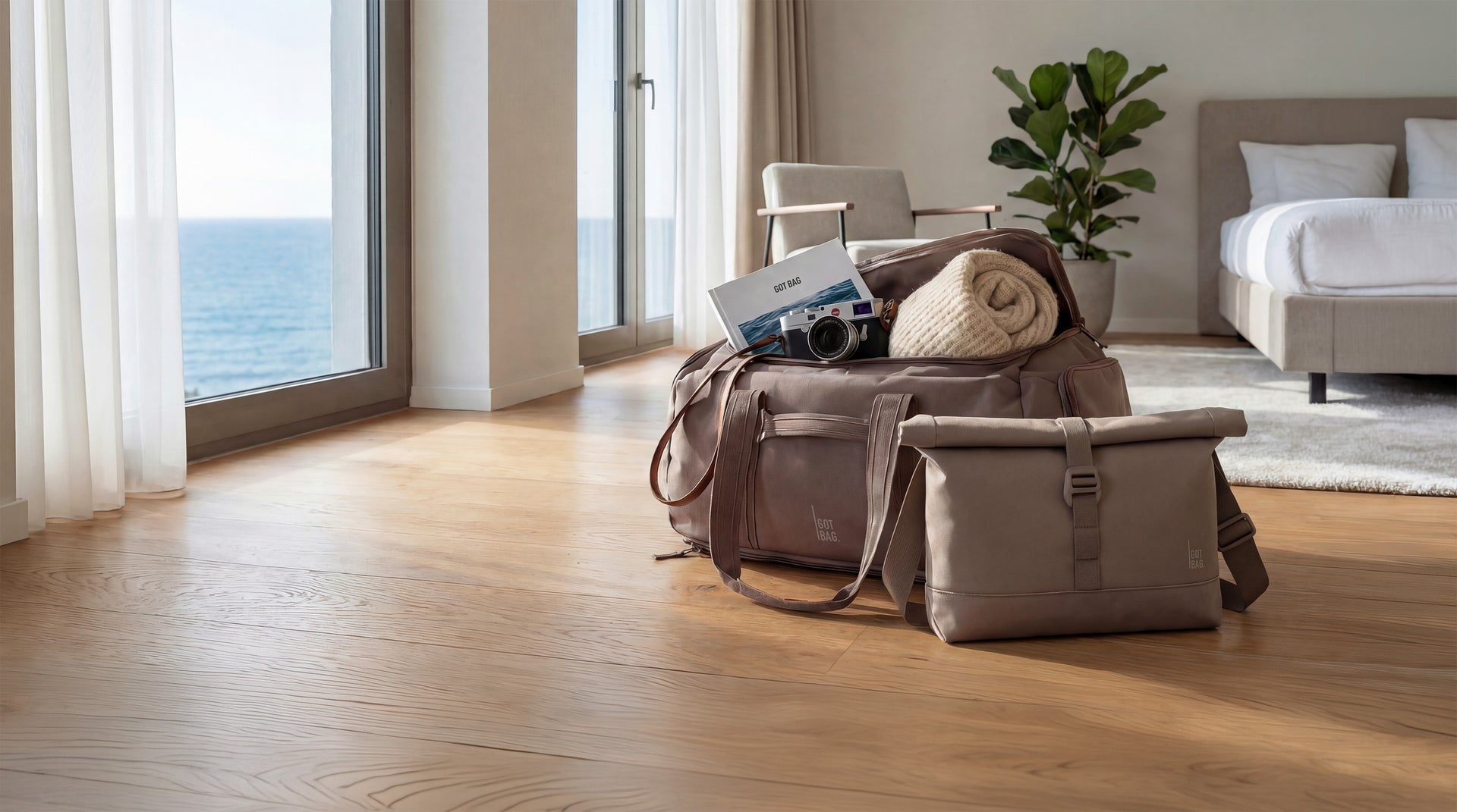 Dvě tašky na dřevěné podlaze. Velká cestovní taška otevřená s knihou, dekou, fotoaparátem. Taška přes rameno vedle.