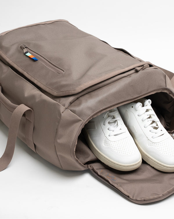 Doplněk s bílými teniskami v otevřené tašce, zip s barevným jezdcem.