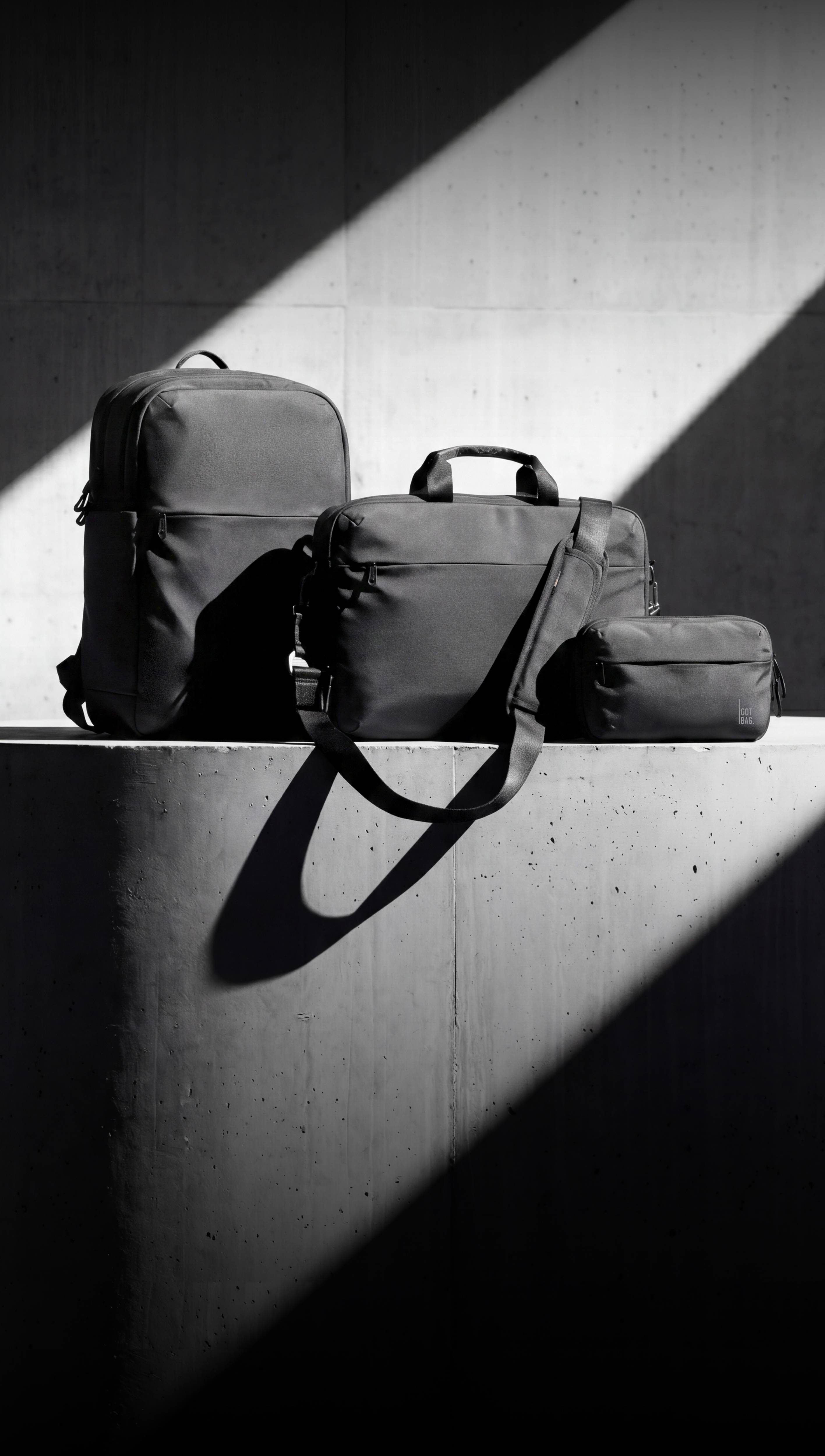 Accessoires: Rucksack, Umhängetasche und kleiner Beutel auf Beton mit Licht und Schatten.