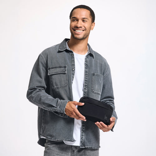 COMMUTER TECH POUCH Accessoire in black (Schwarz) von einem Mann in der Hand gehalten.