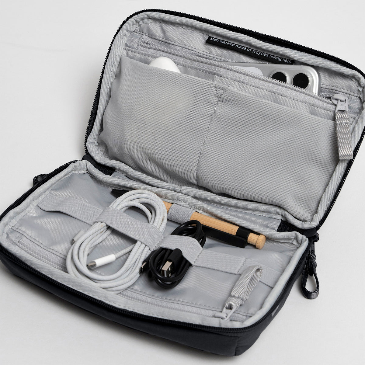 COMMUTER TECH POUCH Tasche in black (Schwarz) als offene Innenansicht mit Zubehör.