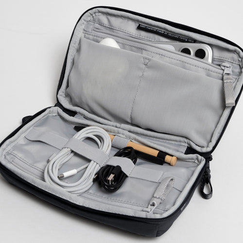 COMMUTER TECH POUCH Tasche in black (Schwarz) als offene Innenansicht mit Zubehör.