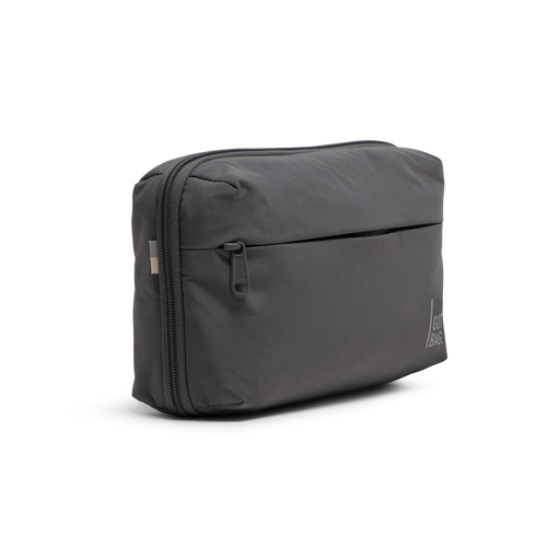 COMMUTER TECH POUCH Tasche in shark (Dunkelgrau) als Studioaufnahme in schräger Ansicht.