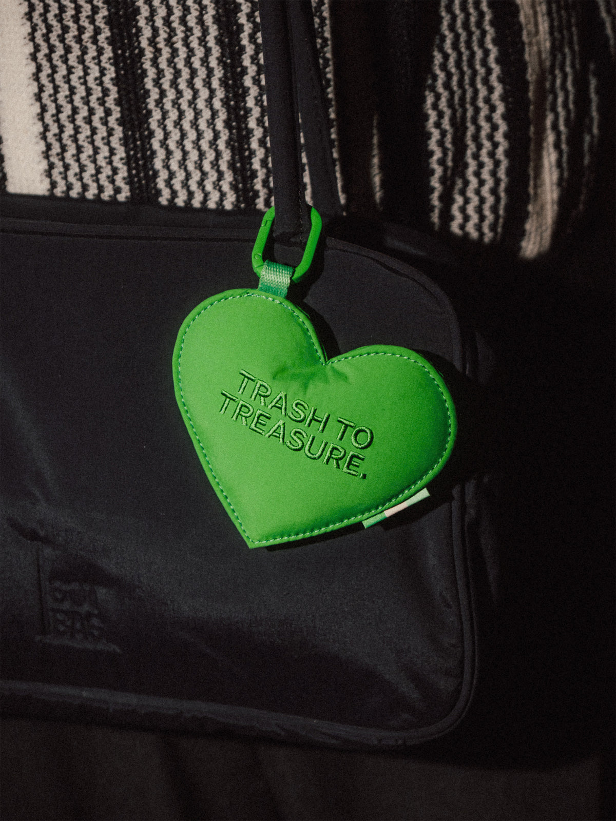 TREASURE CHARM Accessoire, Herzanhänger mit Schriftzug TRASH TO TREASURE an einer Tasche.
