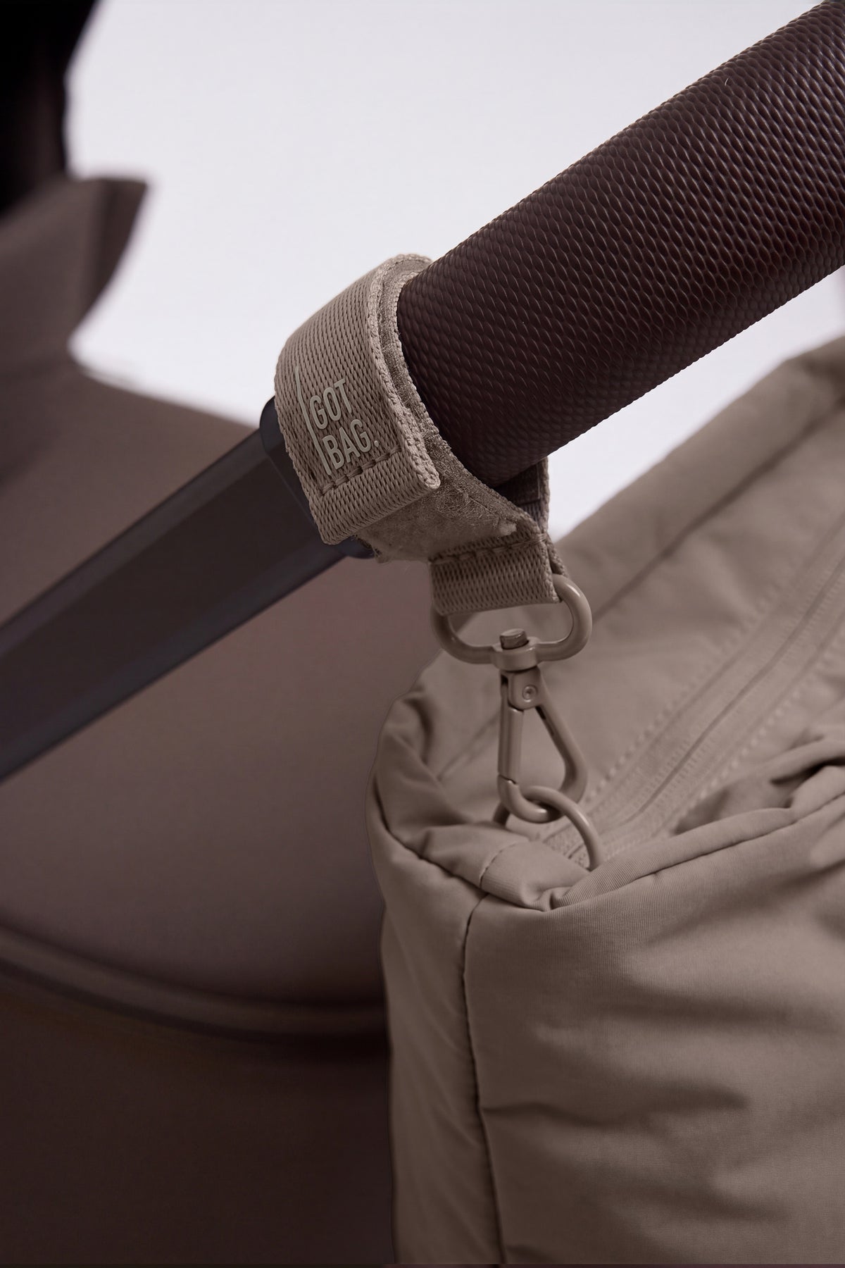STROLLER STRAP Accessoires in oyster (klassisches Taupe-Braun) als Detailaufnahme an einem Kinderwagen.