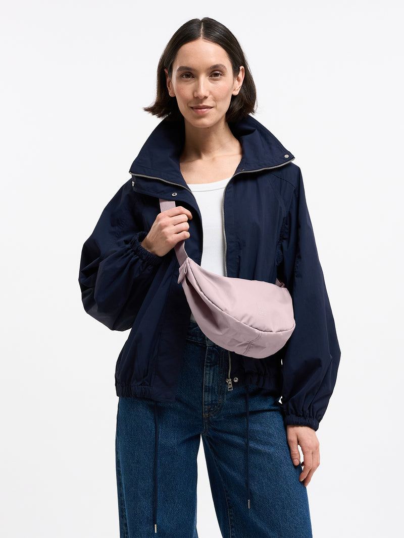 MOON BAG SMALL MONOCHROME Tasche in pink dolphin (blasses Hellrosa) von einer Frau crossbody getragen.