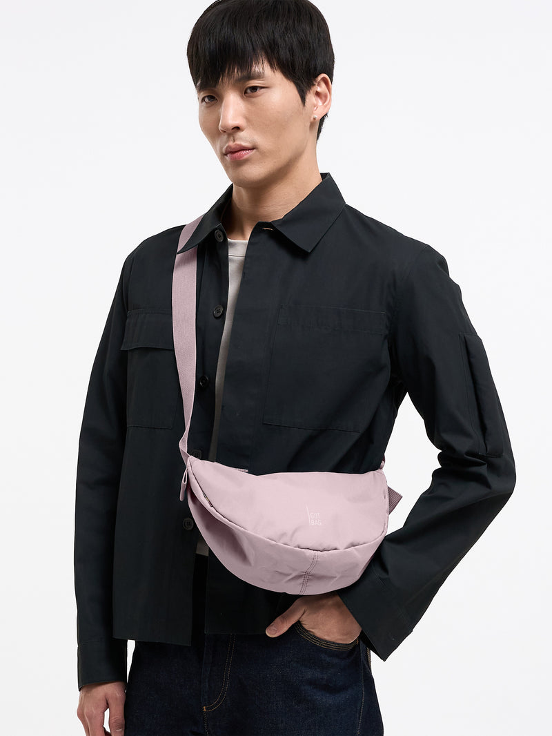 MOON BAG SMALL MONOCHROME Tasche in pink dolphin (blasses Hellrosa) von einem Mann crossbody getragen.