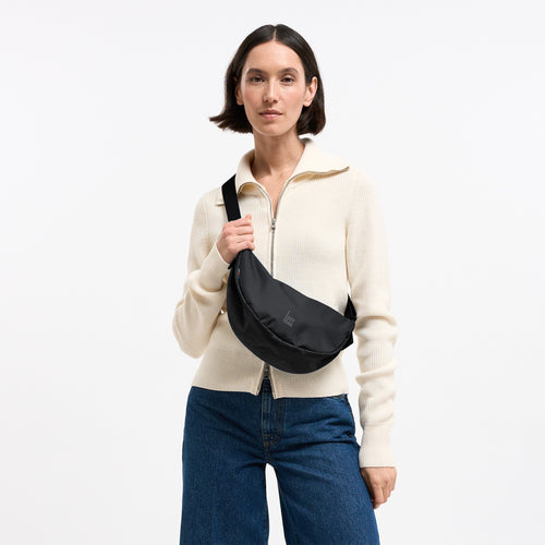 MOON BAG SMALL Tasche in black (Schwarz) von einer Frau crossbody getragen.