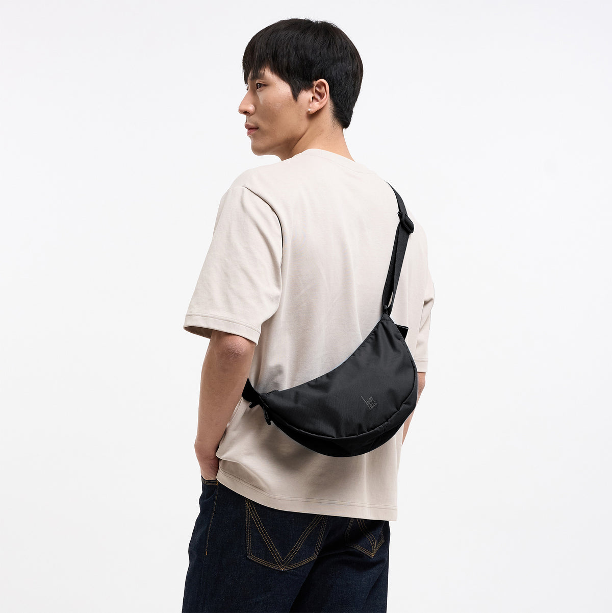 MOON BAG SMALL Tasche in black (Schwarz) von einem Mann crossbody getragen.