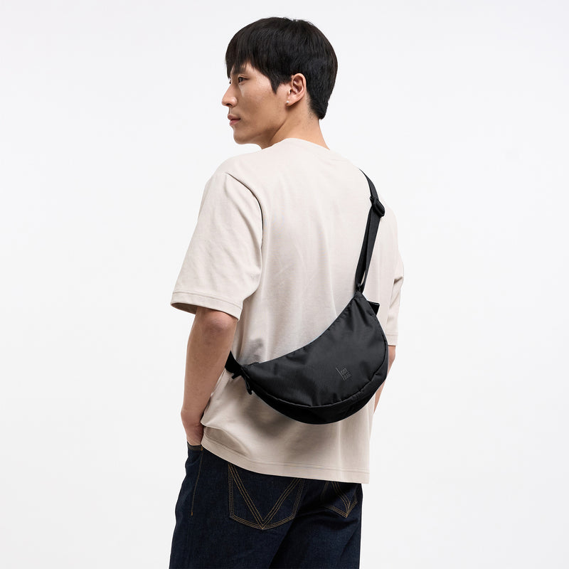 MOON BAG SMALL Tasche in black (Schwarz) von einem Mann crossbody getragen.
