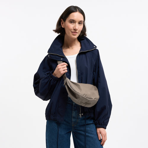 MOON BAG SMALL Tasche in seal (dunkler Beigeton) von einer Frau crossbody getragen.