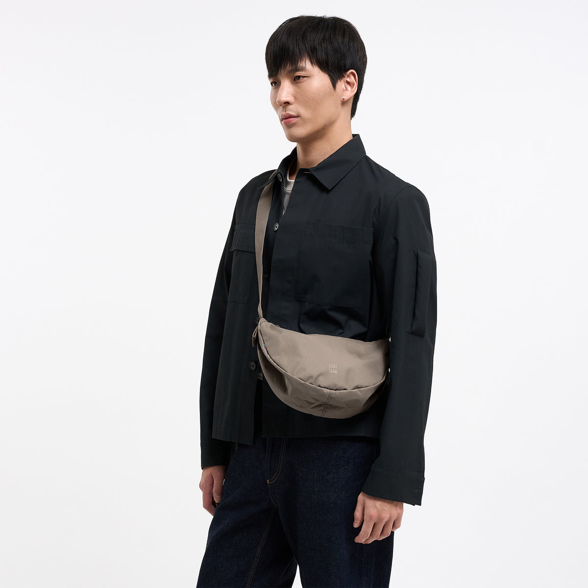 MOON BAG SMALL Tasche in seal (dunkler Beigeton) von einem Mann crossbody getragen.