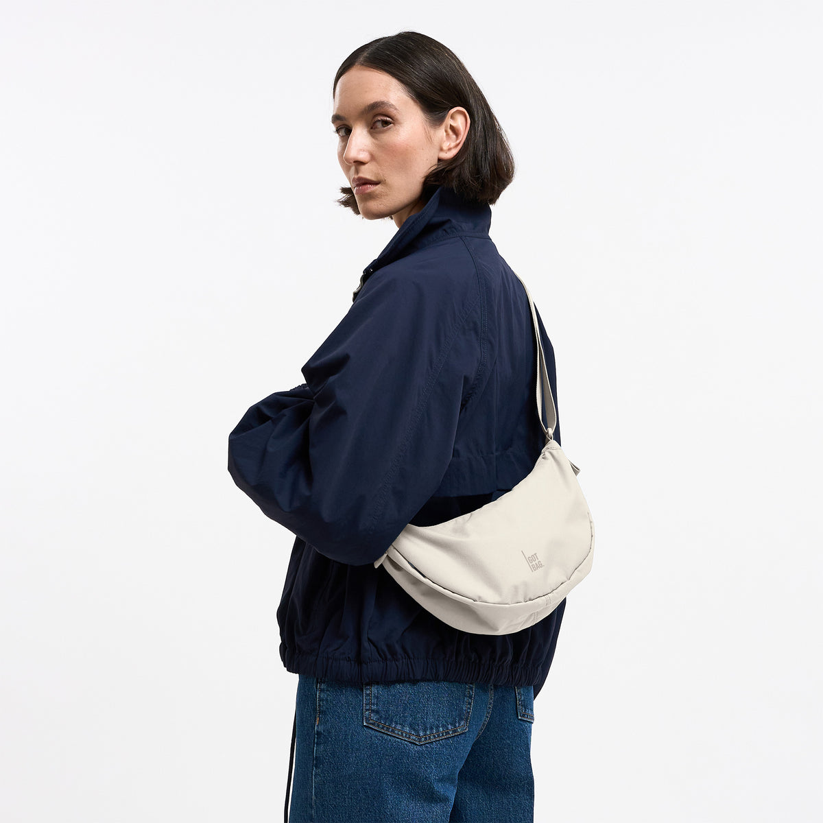 MOON BAG SMALL Tasche in soft shell (warmes Cremeweiß) von einer Frau crossbody getragen.