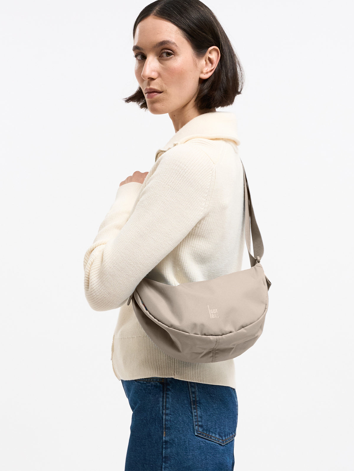 MOON BAG SMALL Tasche in scallop (helles Beige) von einer Frau crossbody getragen.