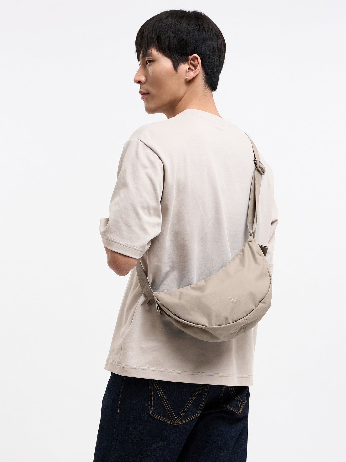 MOON BAG SMALL Tasche in scallop (helles Beige) von einem Mann crossbody getragen.