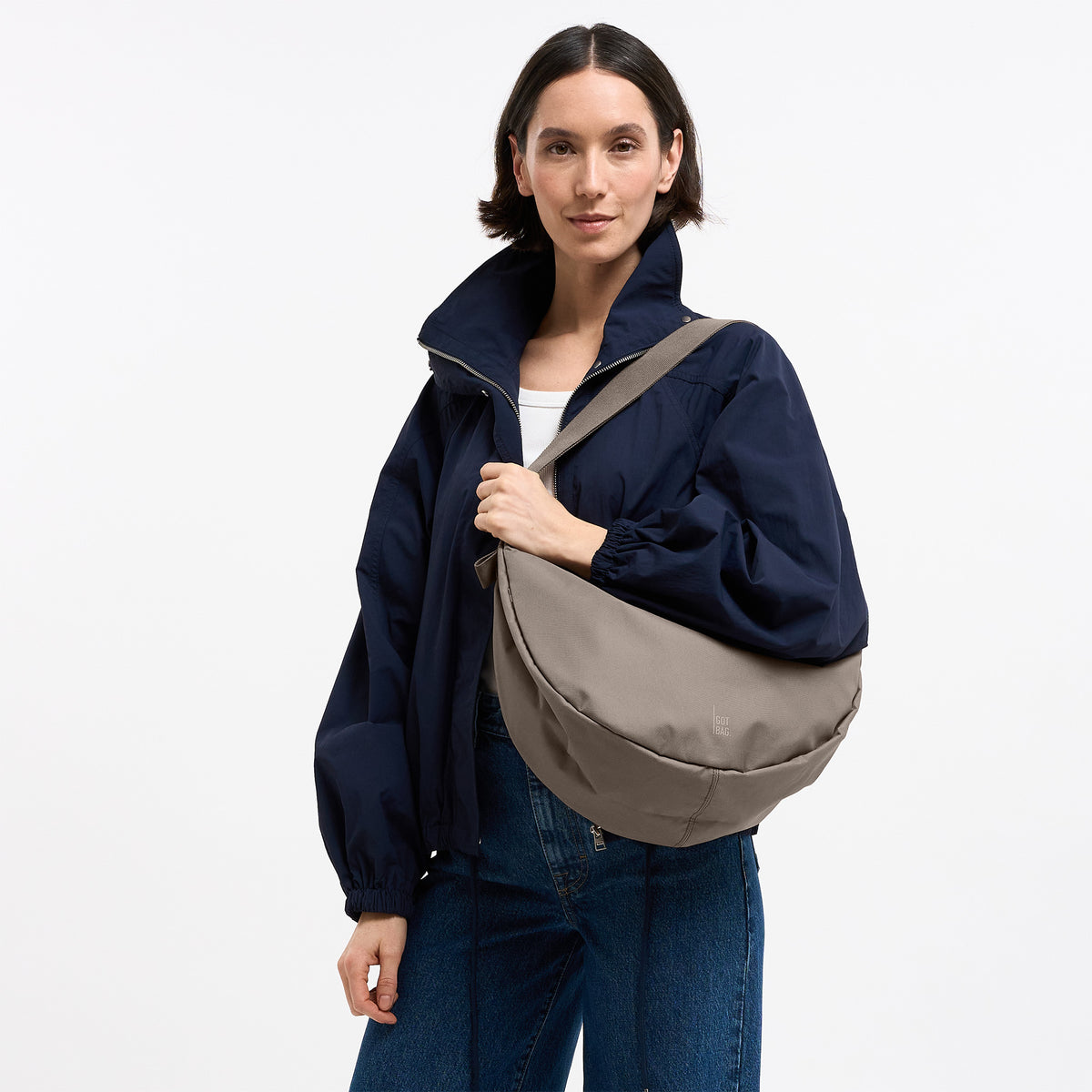 MOON BAG LARGE MONOCHROME Tasche in seal (dunkler Beigeton) von einer Frau über der Schulter getragen.