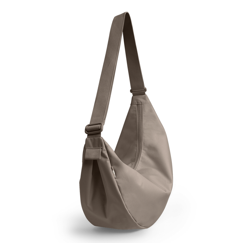 MOON BAG LARGE MONOCHROME Tasche in seal (dunkler Beigeton) als Studioaufnahme, diagonal hängend.