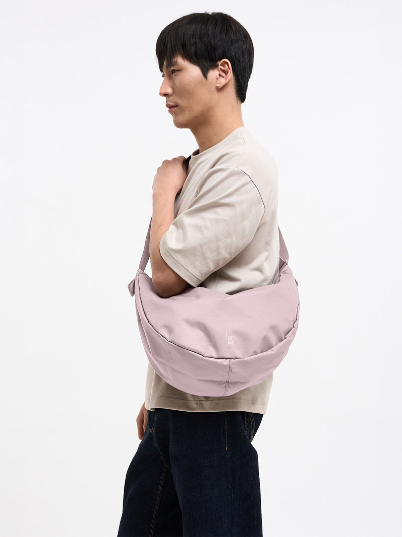 MOON BAG LARGE MONOCHROME Tasche in pink dolphin (blasses Hellrosa) von einem Mann über der Schulter getragen.
