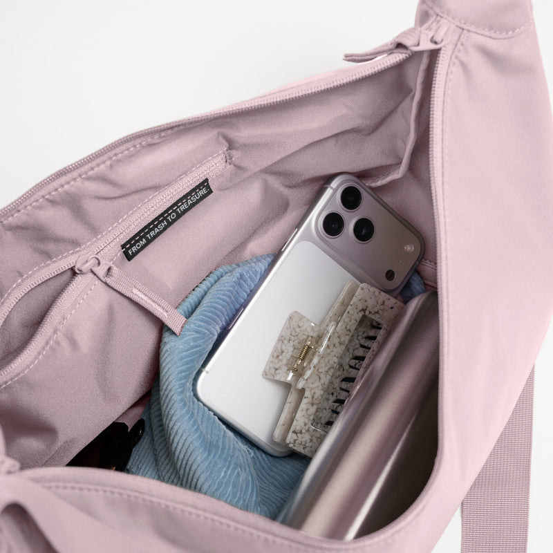 MOON BAG LARGE MONOCHROME Tasche in pink dolphin (blasses Hellrosa) mit Smartphone, Haarklammer und Textil, Etikett From trash to treasure sichtbar.