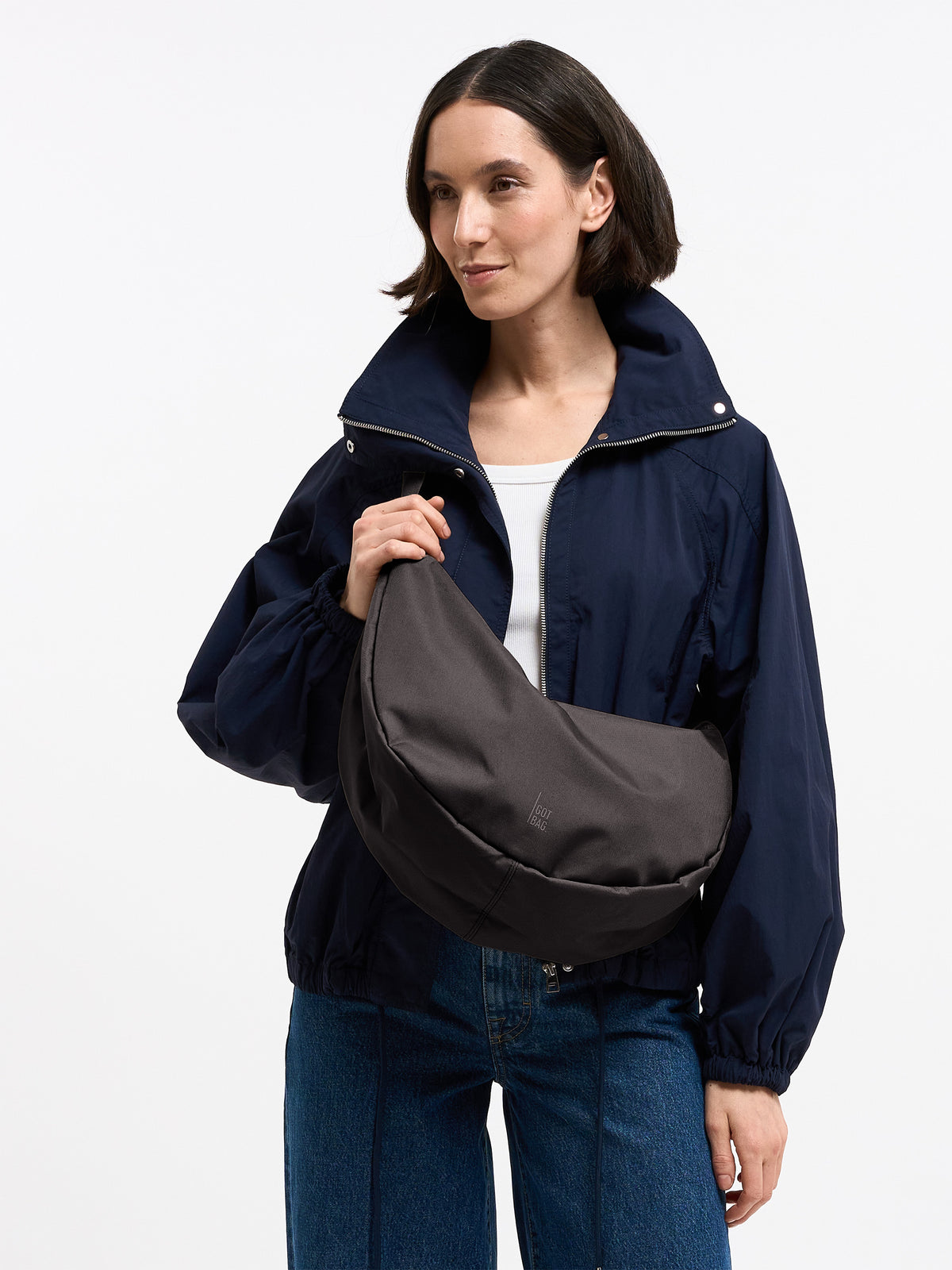 MOON BAG LARGE Tasche in mussel (dunkles Braun-Grau) von einer Frau crossbody getragen.