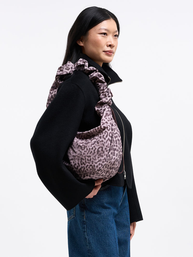 MOON BAG RUFFLE CATSHARK Tasche in sea lion (dunkles Schokobraun) von einer Frau über der Schulter getragen.