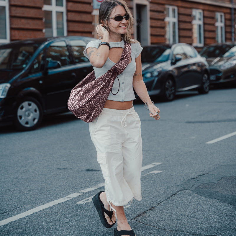 MOON BAG RUFFLE CAT SHARK Tas in sea lion crossbody gedragen door een vrouw.
