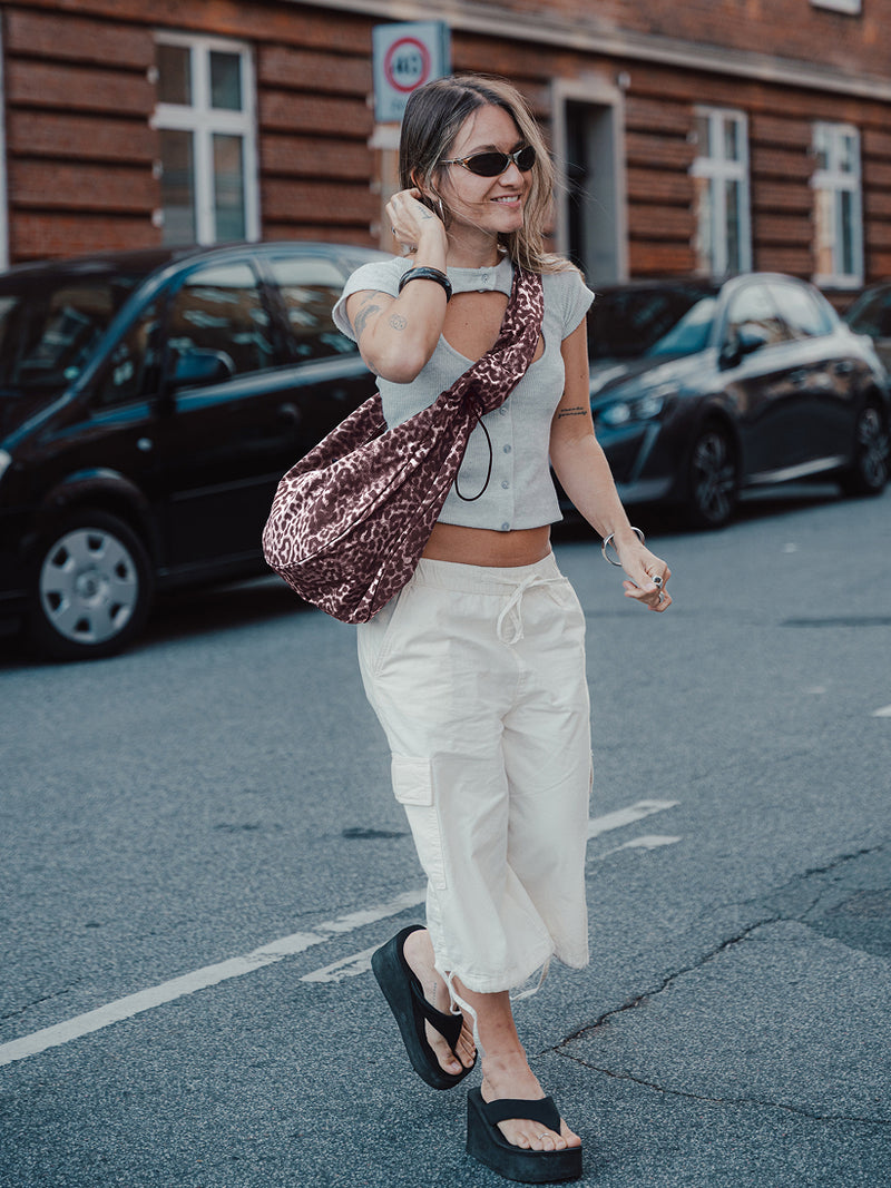 MOON BAG RUFFLE CAT SHARK tas in sea lion crossbody gedragen door een vrouw.