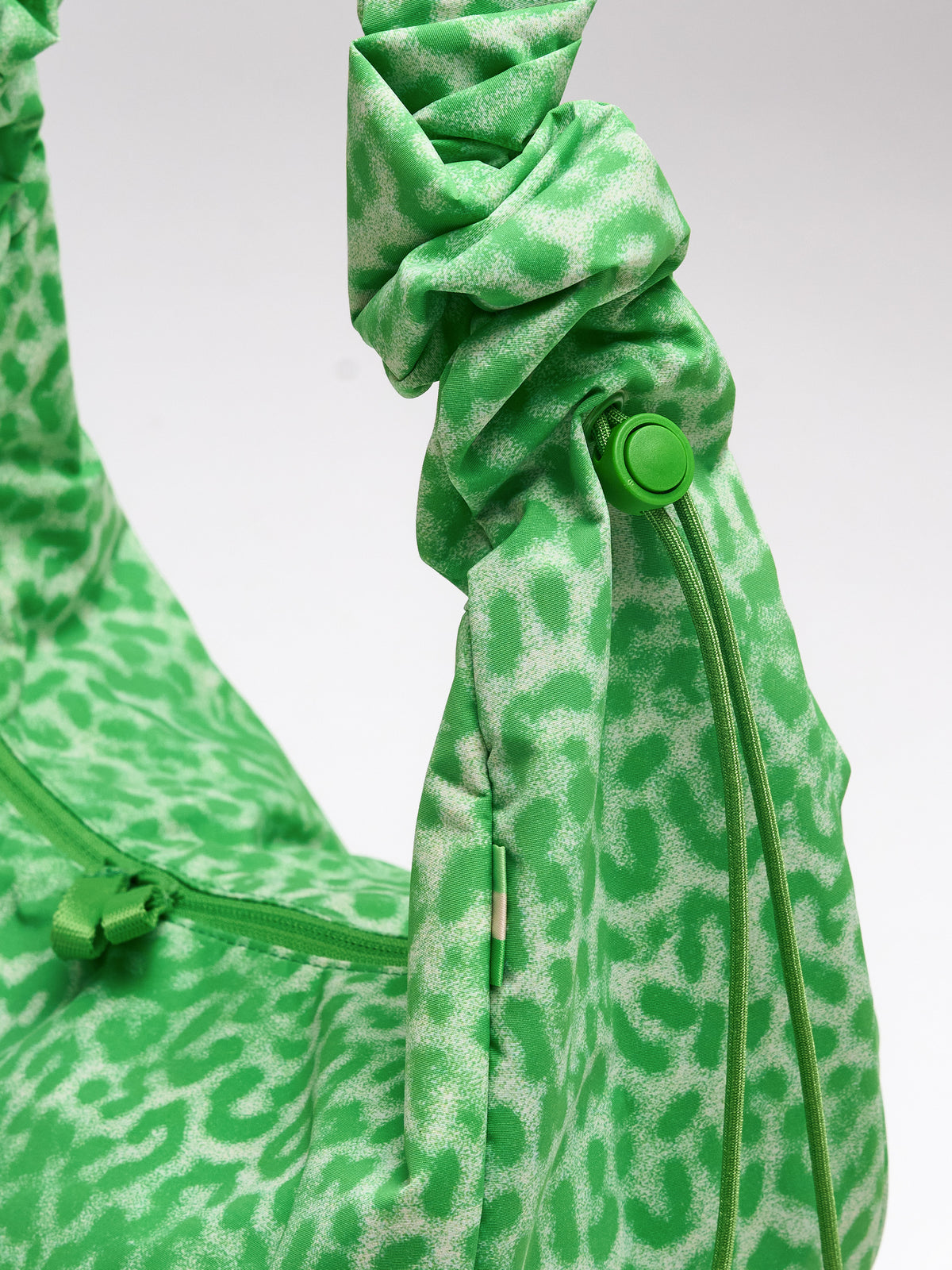MOON BAG RUFFLE CAT SHARK Tasche in leaf als Detailaufnahme mit Kordelzug und Reißverschluss.