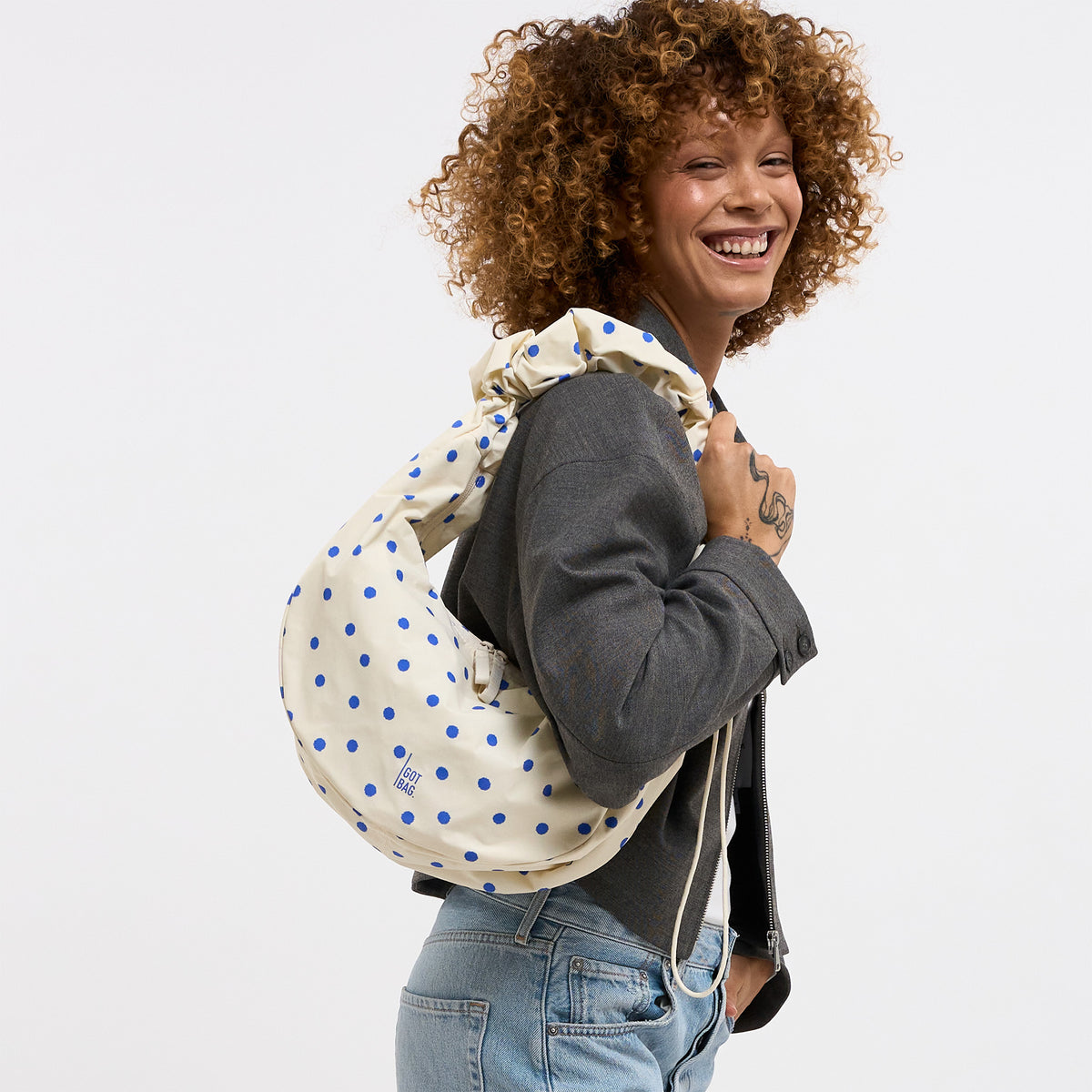 MOON BAG RUFFLE DOT Tasche in cream von einer Frau über der Schulter getragen.