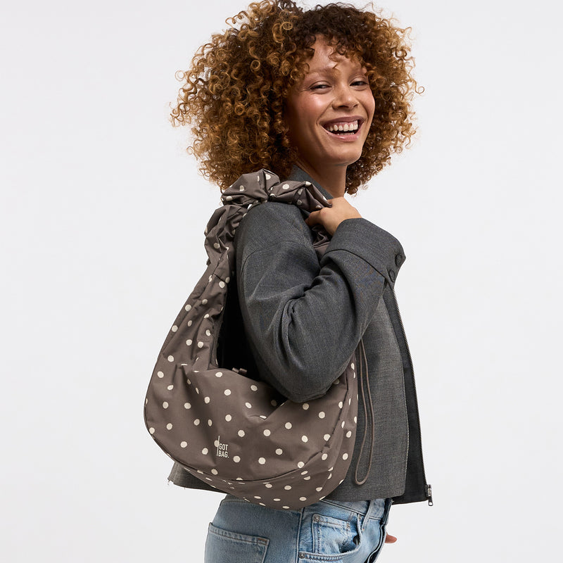 MOON BAG RUFFLE DOT Tasche in oyster (klassisches Taupe-Braun) von einer Frau über der Schulter getragen.