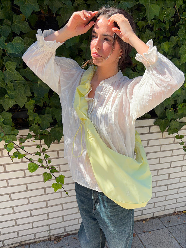 MOON BAG RUFFLE taška v sea lemon (jemná pastelově žlutá) nošená crossbody ženou.