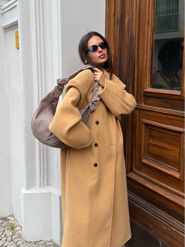 MOON BAG RUFFLE taška v oyster (klasická taupe-hnědá) nošená přes rameno ženy.