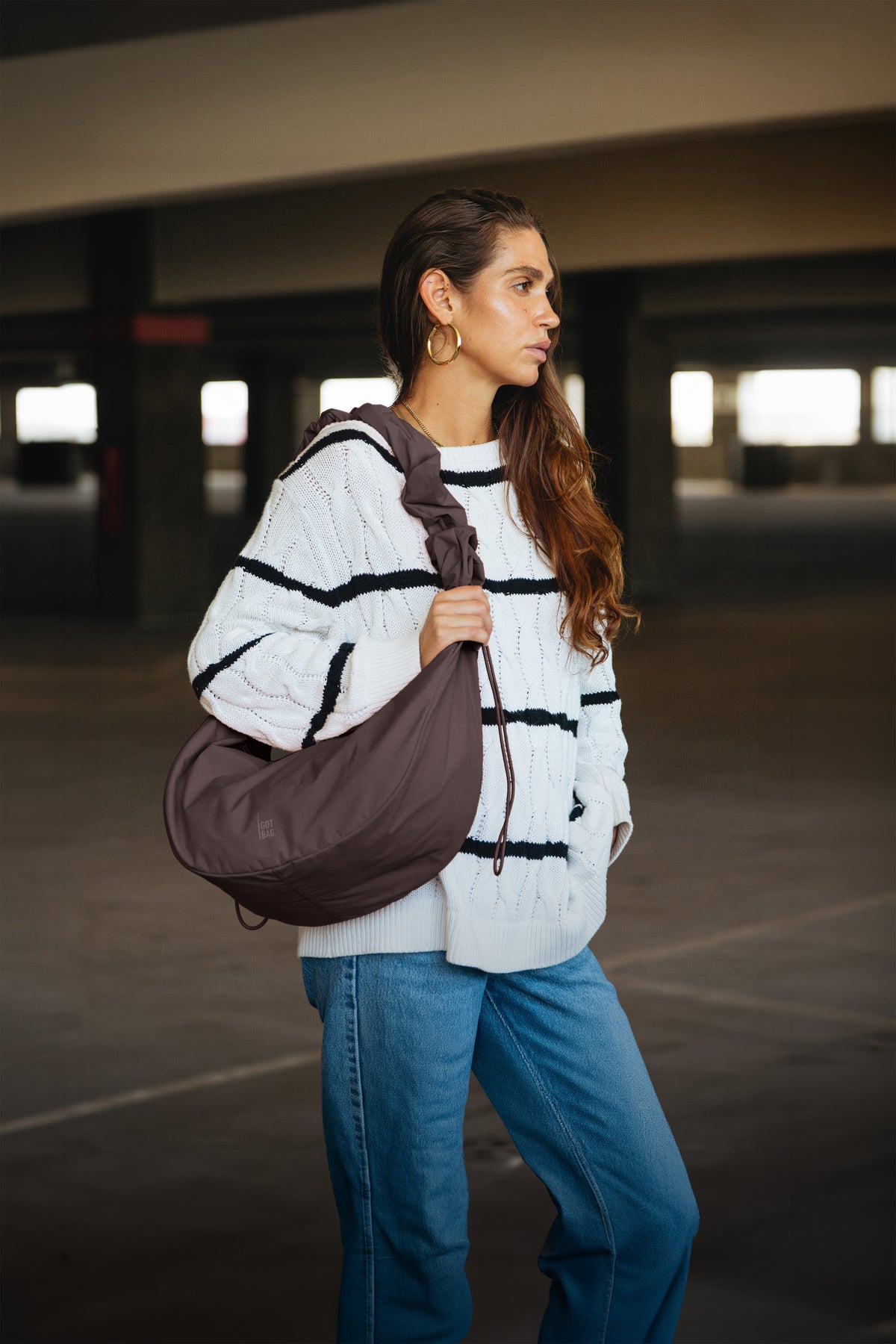 MOON BAG RUFFLE Tasche in sea lion (dunkles Schokobraun) von einer Frau über der Schulter getragen.